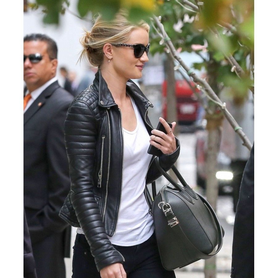 Rear view of a woman wearing a trendy black leather jacket with quilted shoulders, styled with dark jeans and a grey designer handbag.